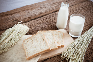 glass of milk and whole wheat bread on the wooden board