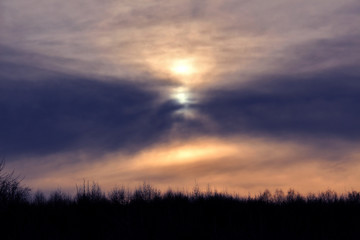 Winter sunset over forest with clouds on evening sky