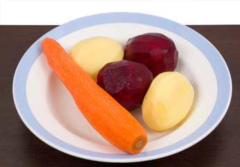 Fresh peeled vegetables for soup in a plate on white background