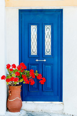 Greek house door in with geranium flowers