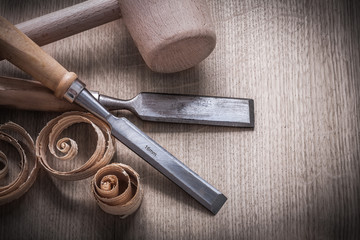 Wooden hammer planning chips flat chisels on wood board top view