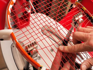 Deurstickers Racquet stringer weaving cross strings of polyester monofilament string in a Tennis racquet on a electronic tournament constant pull stringing machine with double action clamps, Melbourne 2015 © Stringer Image