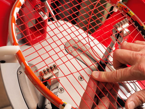 Racquet stringer weaving cross strings of polyester monofilament string in a Tennis racquet on a electronic tournament constant pull stringing machine with double action clamps, Melbourne 2015
