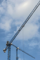Two construction cranes against the sky