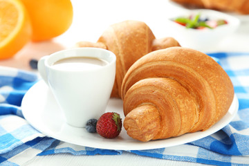 Fresh tasty croissants with berries on white wooden background