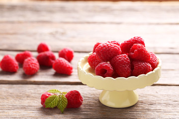 Red raspberries on cake stand on grey wooden background
