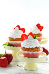 Obraz na płótnie Canvas Tasty cupcake with strawberry on cake stand on white wooden back