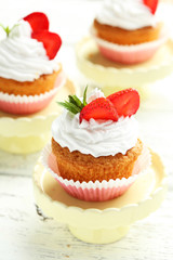 Tasty cupcake with strawberry on cake stand on white wooden back