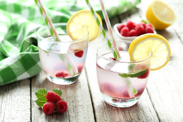 Raspberries and juice in glass on grey wooden background