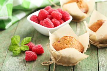 Fresh cupcakes with raspberries on green wooden background