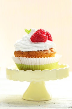 Raspberry cupcake on cake stand on white wooden background