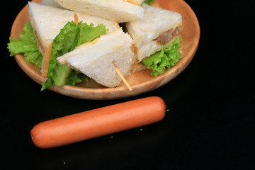 tuna sandwiches and sausage on black background
