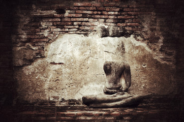Old broken Buddha statue on grunge brick wall background with vi