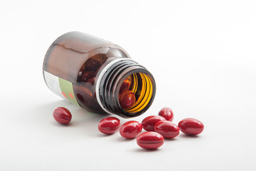 Bottle of red pills on white background