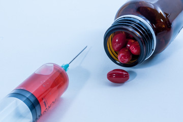 Syringe and red capsules with brown bottle