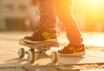 Child with skateboard on the street at sunset light. © Andrii IURLOV