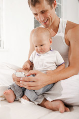 young father with his nine months old son on the bed at home