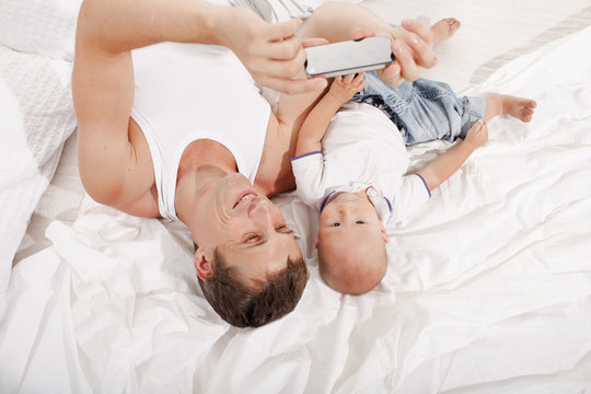 young father with his nine months old son on the bed at home