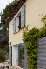 Fototapeta na wymiar House facade with shutters and vine