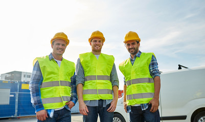 happy male builders in high visible vests outdoors