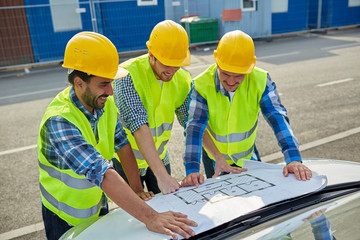 close up of builders with blueprint on car hood