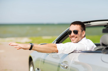 happy man driving cabriolet car and waving hand