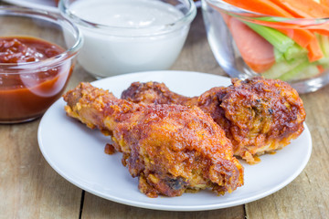 Roasted chicken served with celery and carrot sticks, blue cheese dressing and hot sauce