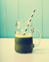 Green smoothie in masons jar with paper straw