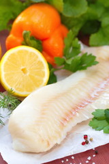 Raw fish with vegetables, lemon and seasonings on the wooden table