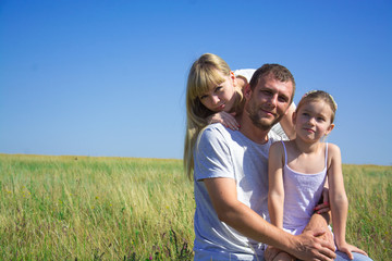 Young happy family in a field of a mom dad daughter