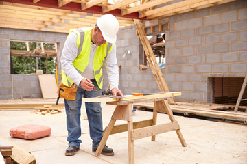 Carpenter Cutting House Roof Supports On Building Site