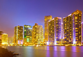 City of Miami Florida, night skyline. Cityscape of residential and business buildings illuminated at sunset with reflection
