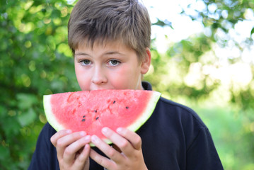 Teen boy eating watermelon in nature