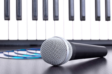 Microphone, cd disks and piano keyboard on black table