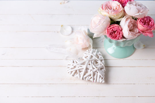 Pastel roses in turquoise vase  and decorative heart on white wo