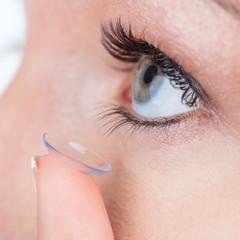 Woman eye with contact lens applying