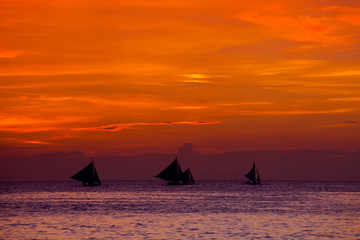 Sunset on beach with sailing boats