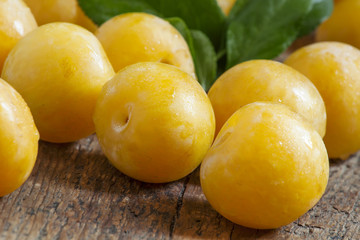 Ripe yellow plums on old wooden background, selective focus