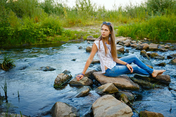 Boho Girl sitting on bank of  river.