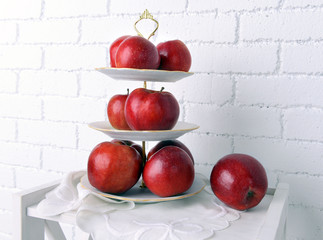 Tasty ripe apples on serving tray on brick wall background