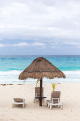 Sun umbrella and beds on caribbean beach in cloudy weather