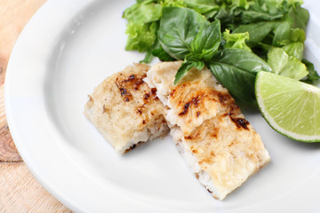 Dish of fish fillet with greens and lime on plate close up