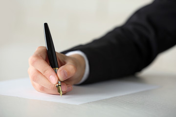 Female hand with pen writing on paper at workplace