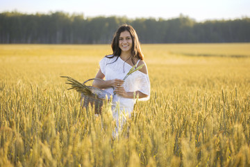 Smiling beautiful girl in field with basket and wheat grass
