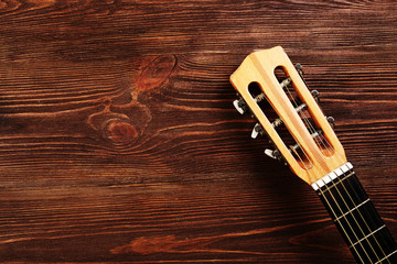 Neck of acoustic guitar on wooden background