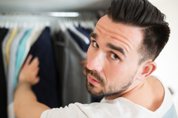 Man tired of choosing clothes during shopping