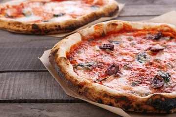 Delicious pizzas on wooden table, closeup