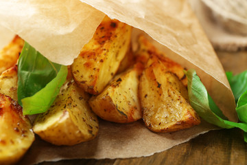 Baked potatoes in parchment on wooden table, closeup