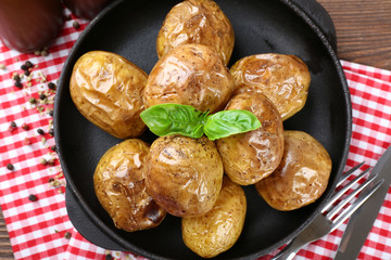 Baked potatoes in pan on wooden table, closeup