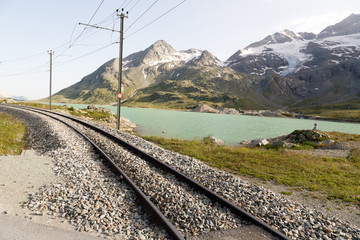 Fototapeta na wymiar Rotaie treno Bernina express su lago bianco